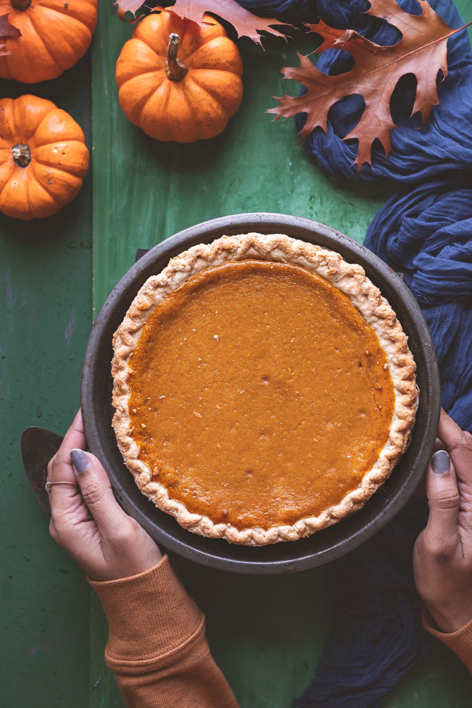 Picture of a pumpkin pie, with pumpkins on the side of it.